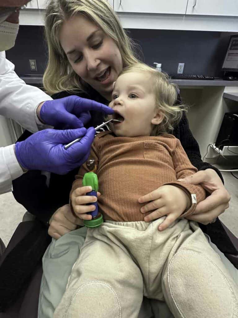 Dr.Kapp examining the teeth of a young child who is sitting in the dental chair during a check-up.